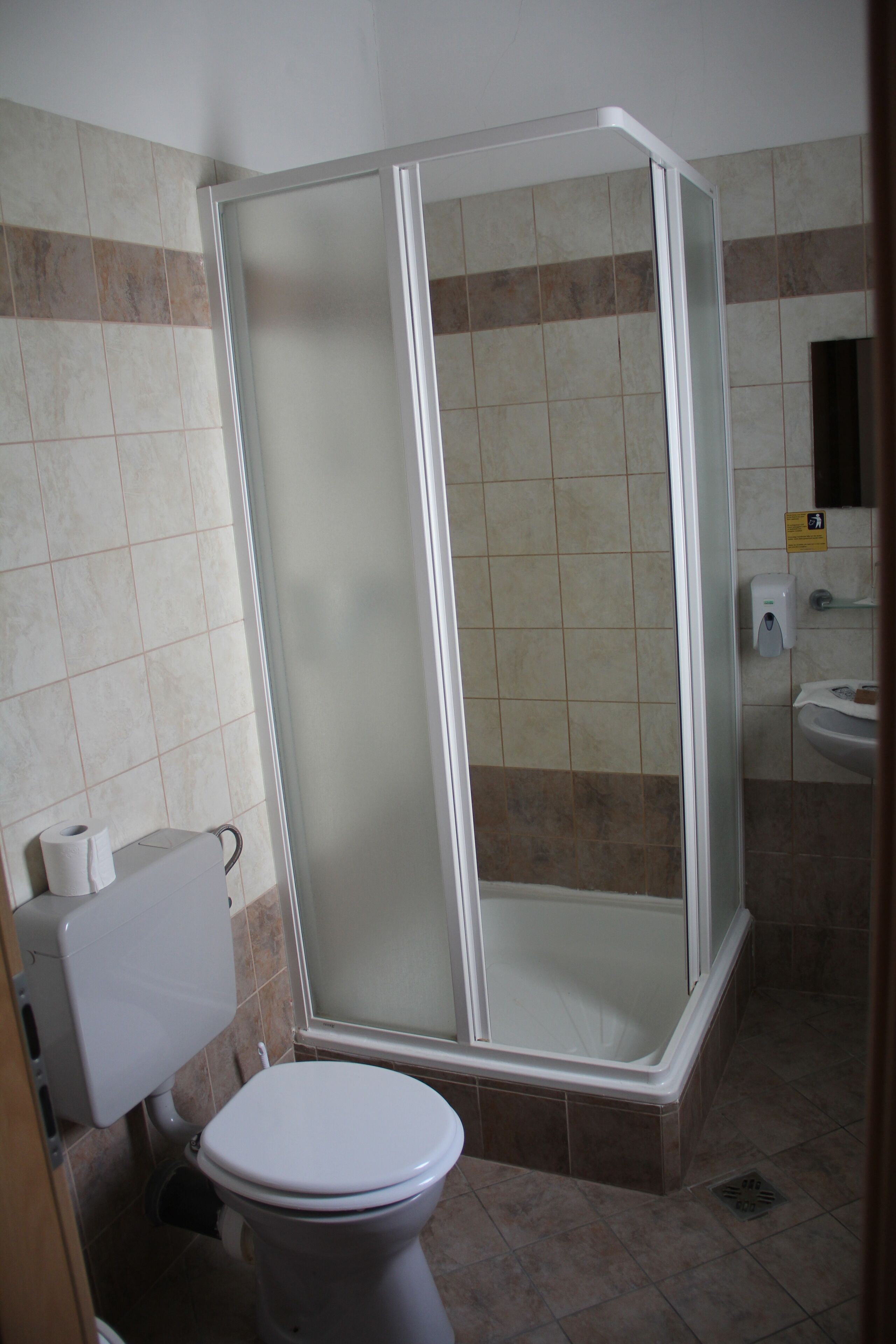 A bathroom with a toilet, a shower enclosure, and a sink.