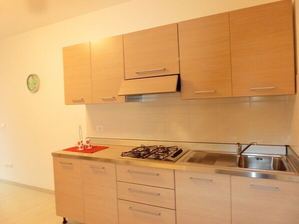 A kitchen with wooden cabinets, a gas stove, and a sink.