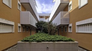 A courtyard with a central planter, surrounded by buildings with balconies and windows. - Spacious flat surrounded by nature - Beahost (Bibione)