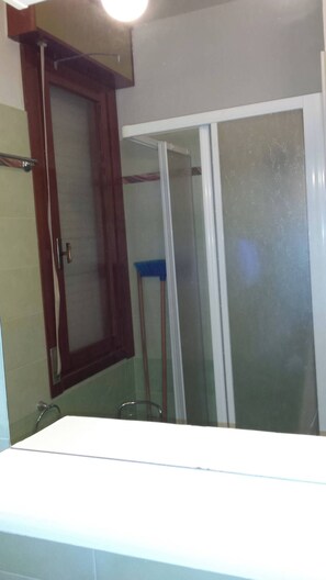 A bathroom with a glass shower enclosure, a wooden cabinet, and a visible towel rack. - Nice three-bedroom flat with balcony in Bibione (Bibione)