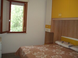 Una camera da letto con un letto, una finestra, un armadio e una piccola scrivania.