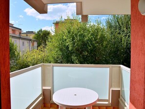 Un balcón con una mesa redonda y una barandilla de cristal.