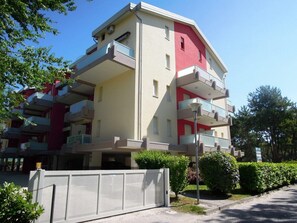 Un immeuble résidentiel à plusieurs étages, doté de balcons, d’une entrée sécurisée et entouré de verdure.