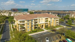Un immeuble résidentiel à plusieurs étages doté d’une cour intérieure, d’un parking et offrant une vue sur les environs, notamment sur d’autres immeubles et un chantier de construction.