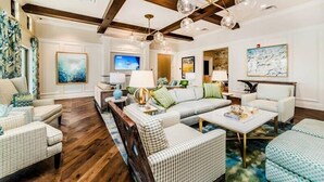 A spacious living room with a large sofa, armchairs, and a coffee table. There are multiple lamps and a television. - Relax & Play: Spacious Themed Retreat in Solara (Kissimmee)