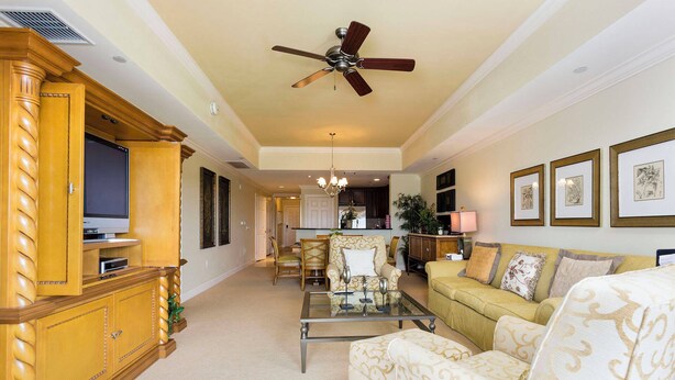 A spacious living room with a television, a ceiling fan, a dining area, and a kitchen in the background. - Serenity Apt - Tranquil and Cozy Orlando Apartment (Kissimmee)