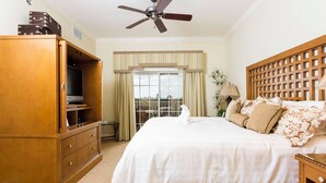 A hotel room with a bed, a wooden wardrobe, a ceiling fan, and a window with curtains. - Serenity Apt - Tranquil and Cozy Orlando Apartment (Kissimmee)