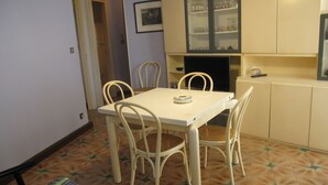 Een klein eetgedeelte met een tafel en vier stoelen, een kast met glazen deuren, en een vloer met een patroon.