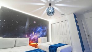 Una camera da letto con un murale raffigurante un cielo stellato, un lampadario e una porta bianca.