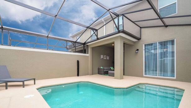 Una piscina interna con tetto in vetro, una poltrona da relax e un’area salotto con cuscini.
