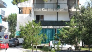A multi-story residential building with balconies, parked cars, and trees in the foreground. - Modern flat at Grado Pineda (Grado Pineta)