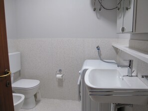 Une salle de bain avec des toilettes, un lavabo et une douche.