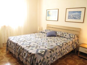 Un lit avec une couvre-lit à motifs, une table de chevet et deux tableaux encadrés accrochés au mur.
