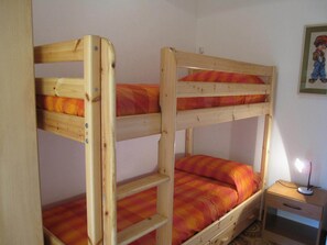 A bunk bed with a nightstand and a lamp.