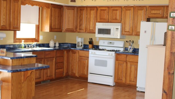 A kitchen with wooden cabinets, a built-in microwave, a stove, and a refrigerator.