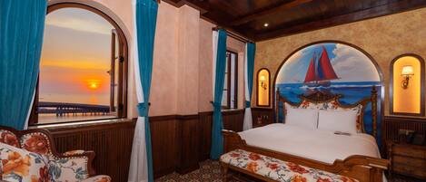 A room with a large window, a bed, a bench, and a wall mural of a sailboat.