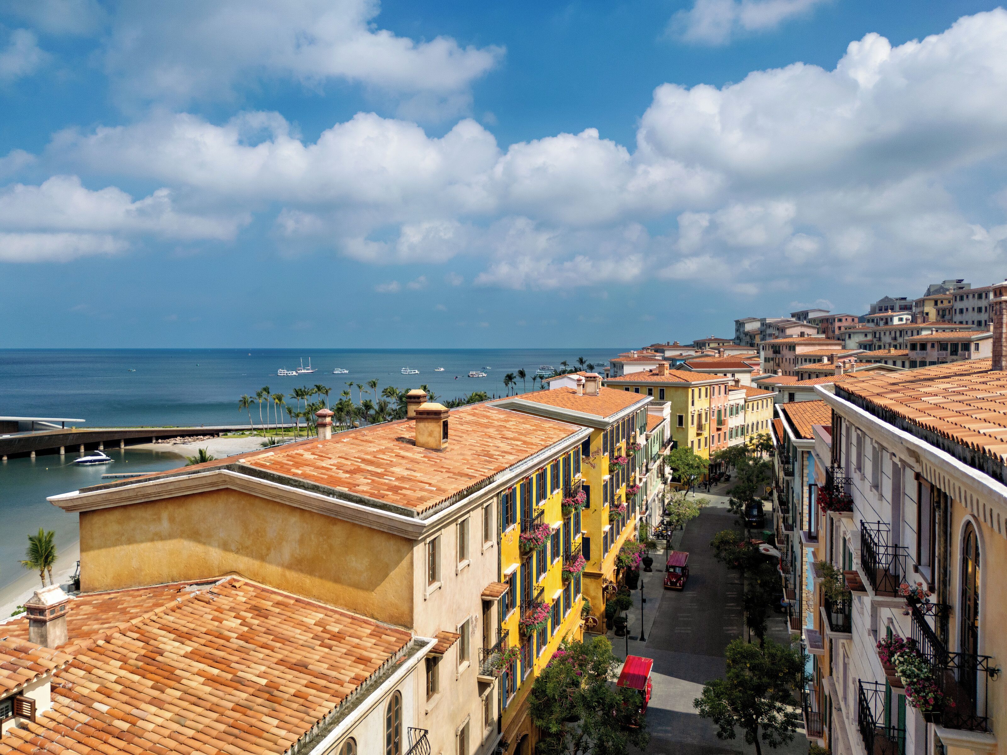 Una calle costera con edificios de colores, un puerto deportivo y barcos.