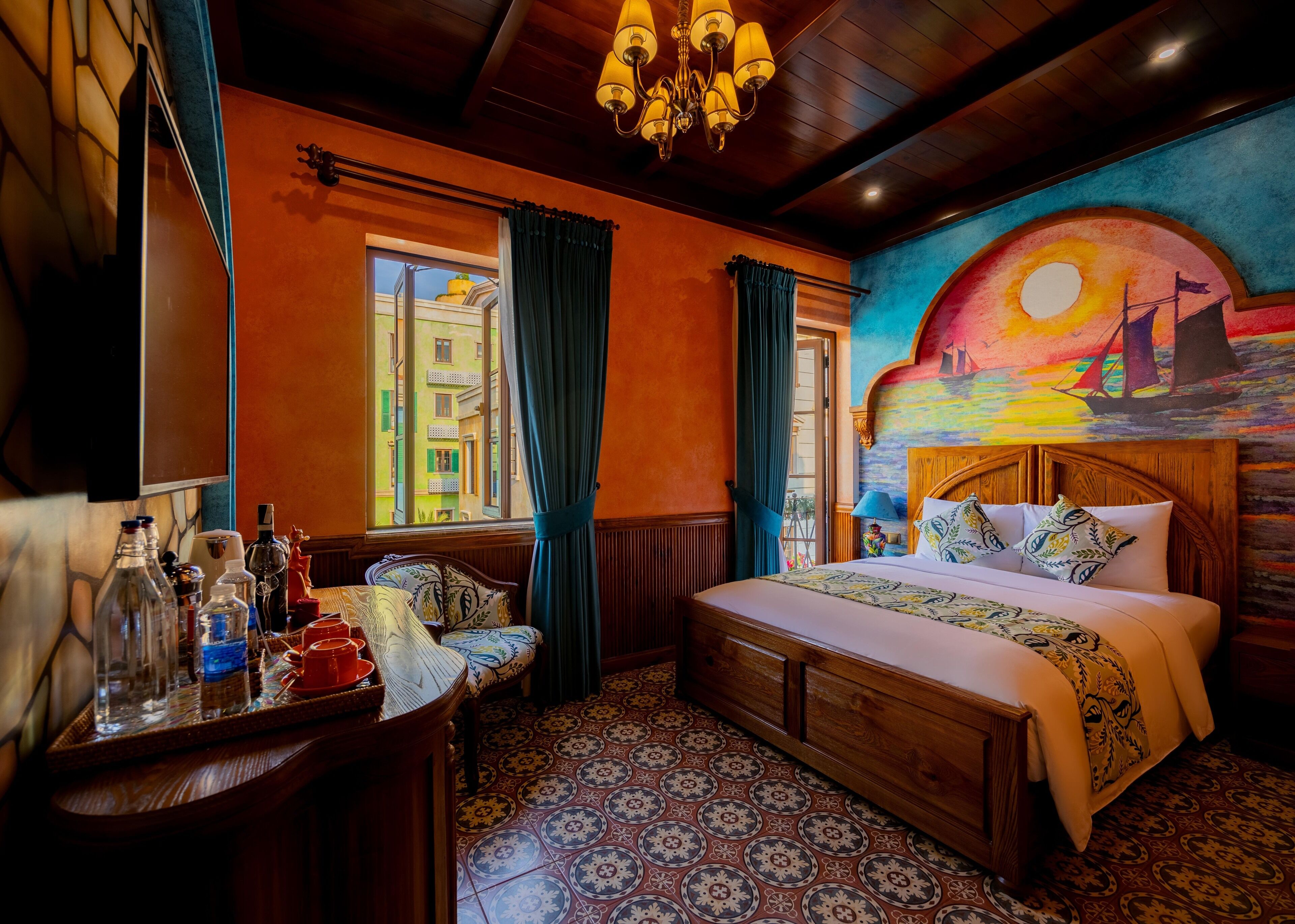 A room with a bed, a chair, a table with bottles, and a window with curtains.