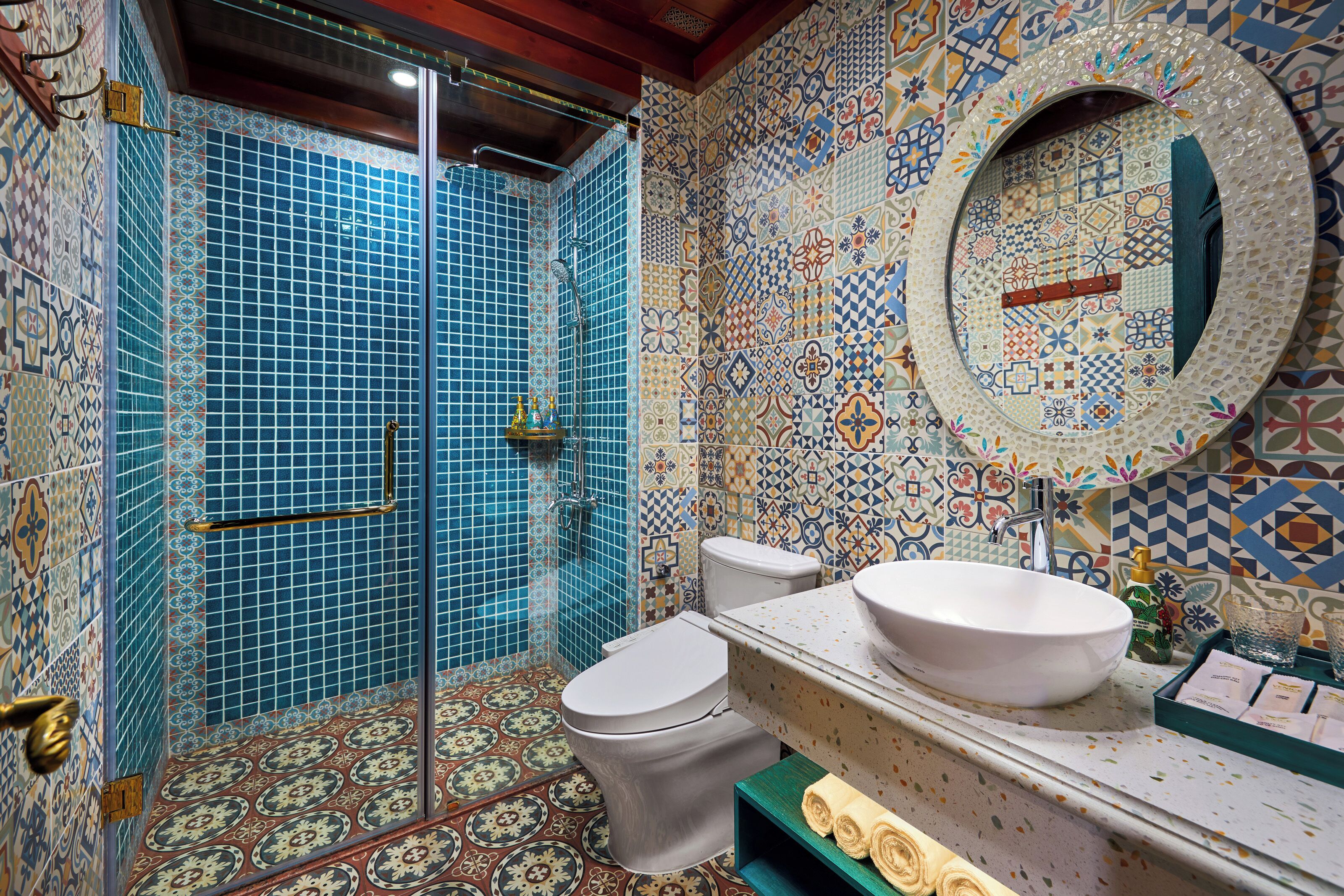 A bathroom with a shower, toilet, sink, and a decorative mirror.