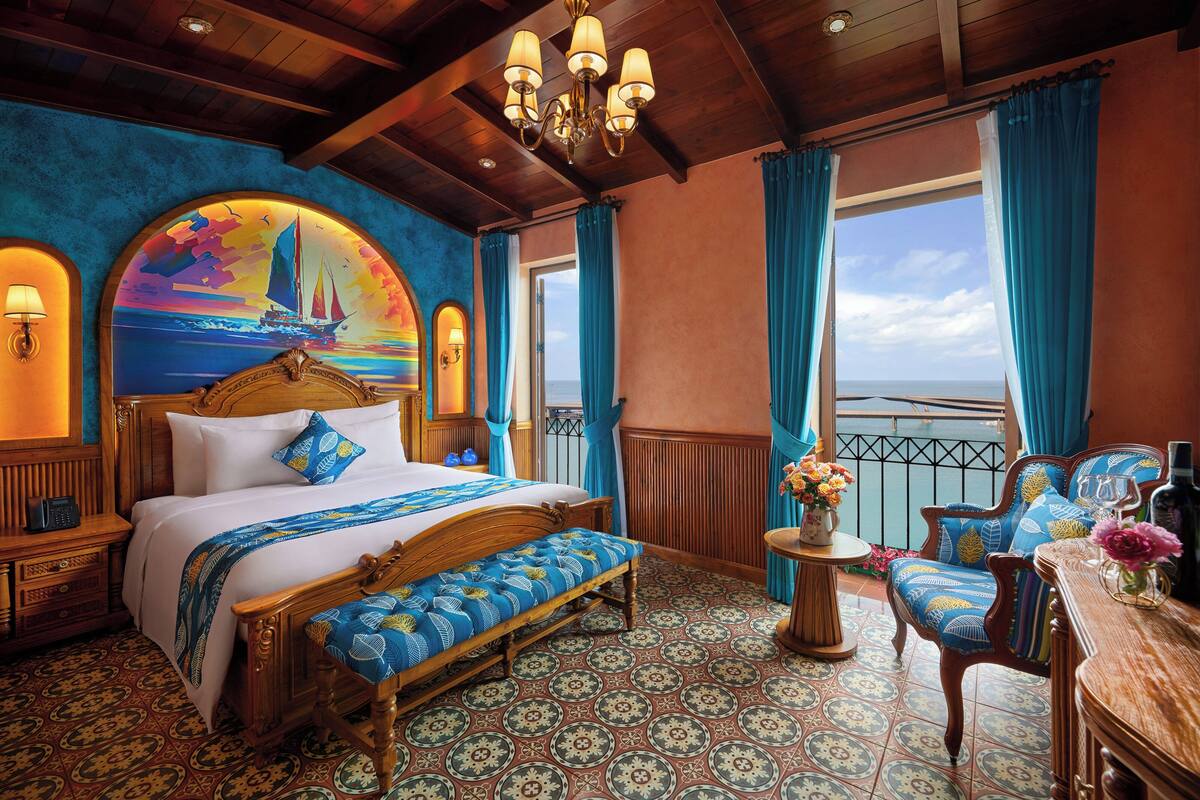 Une chambre avec un lit, un banc, une chaise et une vue sur la mer.