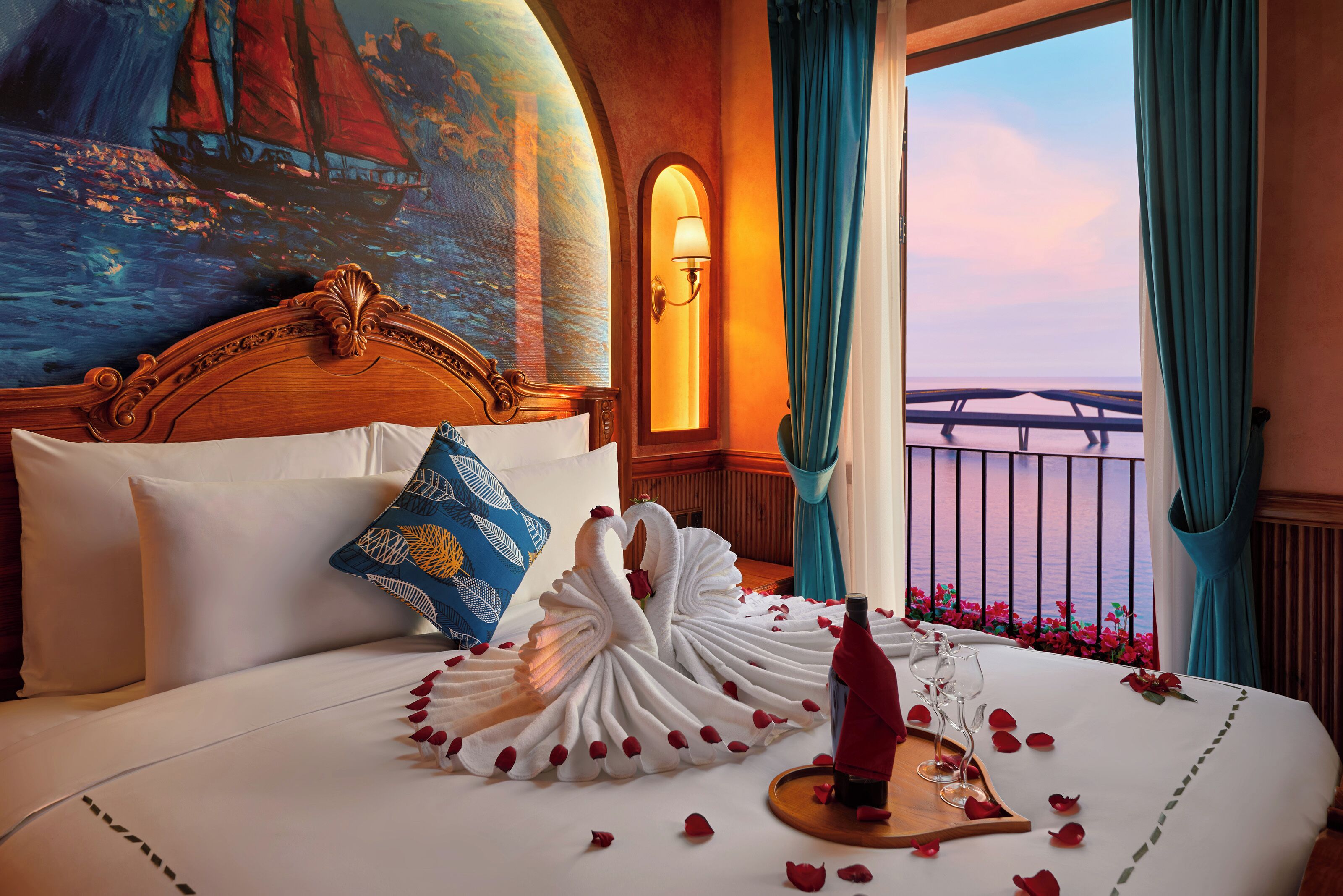 A hotel room with a bed, a painting of a sailboat, a balcony with a railing, and a view of the sea.