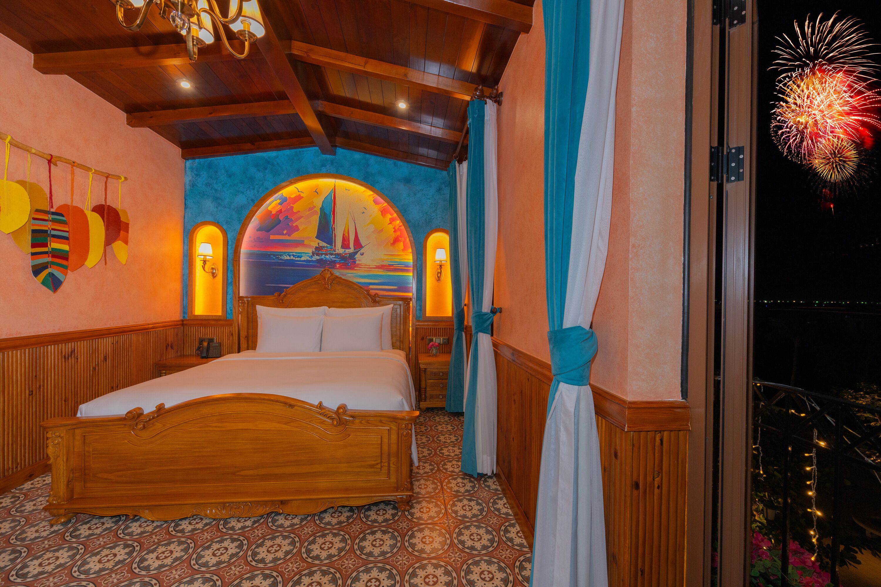 Una habitación con una cama de madera, un mural de un velero y un balcón con vistas a fuegos artificiales.