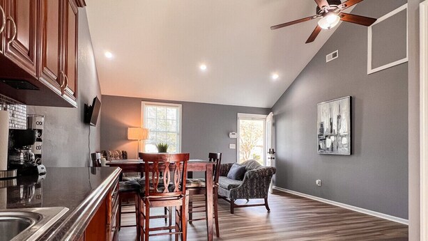 A modern kitchen with wooden cabinets, a dining area with a table and chairs, and a ceiling fan. - Large 2 bedroom | Queen beds | Safe Area (Hampton)