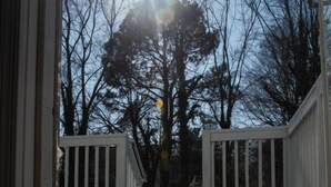 A wooden deck with a white railing, leading to a building. - Large 2 bedroom | Queen beds | Safe Area (Hampton)