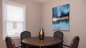 A dining area with a round table, four chairs, a vase, and a painting on the wall. - Perfect for families! (Newport News)