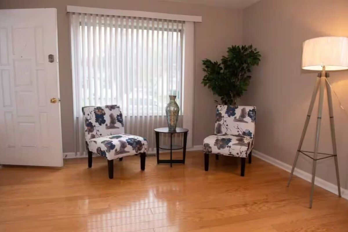 A room with two armchairs, a small table, a floor lamp, and a potted plant.
