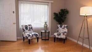 A room with two floral armchairs, a small round table, a potted plant, and a floor lamp. - Perfect for families! (Newport News)