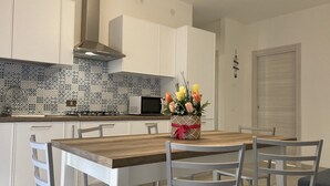 Une cuisine moderne avec des meubles blancs, un pare-feu décoré et une table à manger en bois, accompagnée de chaises.
