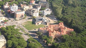 Vue aérienne d’un quartier résidentiel, où l’on aperçoit un bâtiment imposant doté d’une structure centrale circulaire, entouré d’une végétation luxuriante et d’autres immeubles résidentiels.