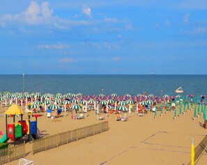Una playa con numerosos paraguas de colores y una zona de juegos.