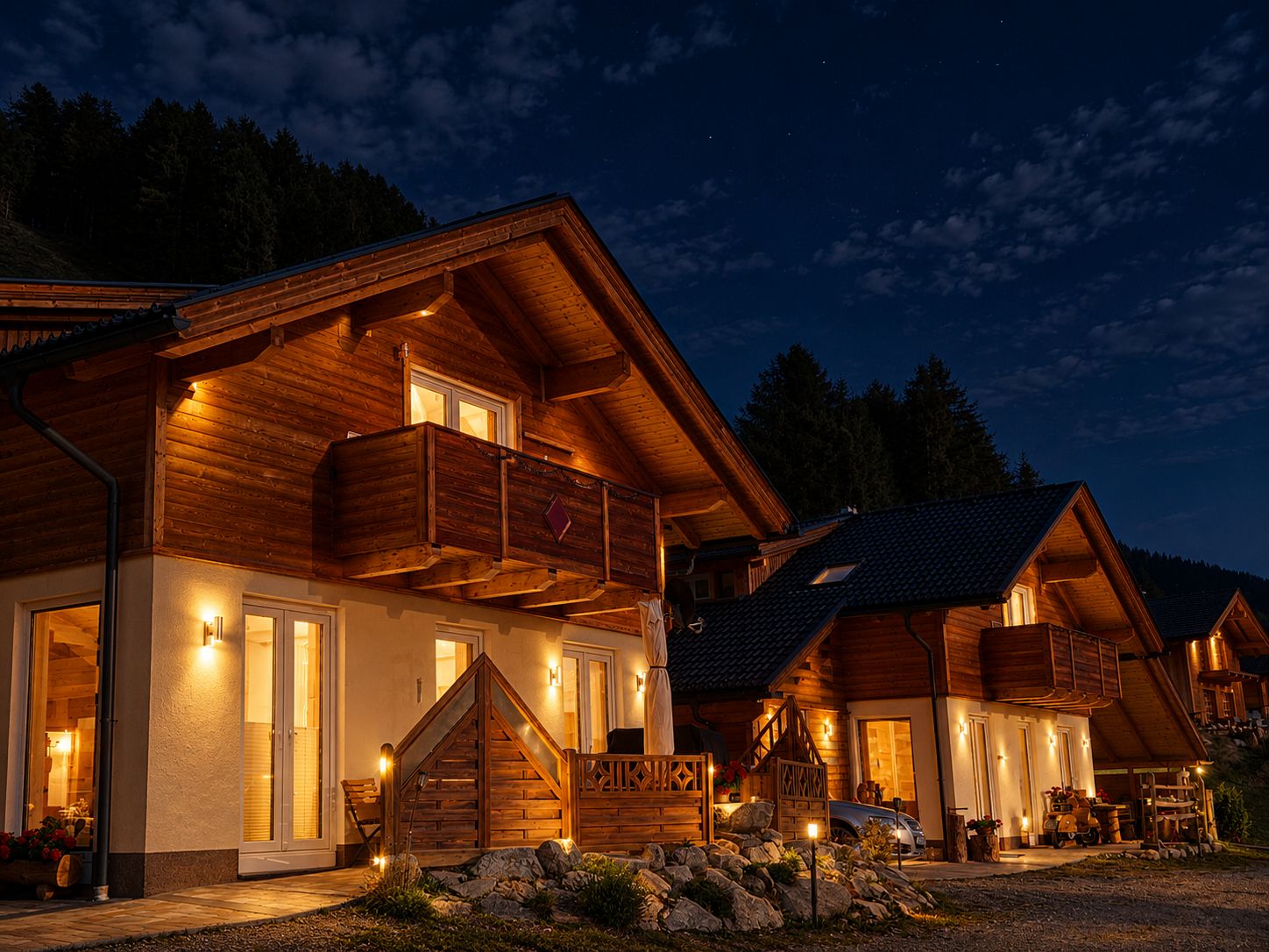 A wooden cabin with a balcony, a staircase, and a car parked outside.