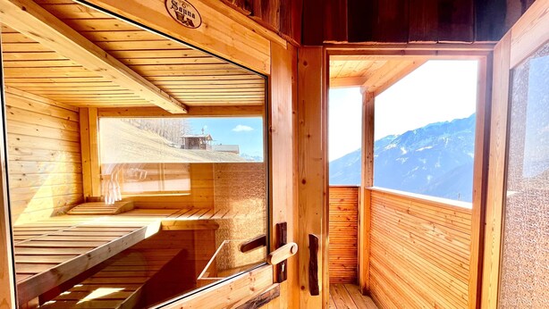 A wooden sauna room with a large window offering a mountain view. - Ferienwohnung Smaragd in Herrlich, Sonniger Höhenlage mit Großglocknerblick (Heiligenblut)