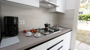 A modern kitchen with a gas stove, coffee maker, and white cabinets.