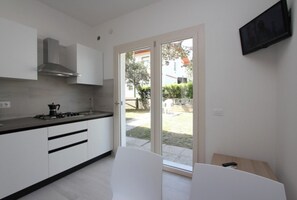 Een koelkast, een kookplaat, kookgerei, borden en bestek