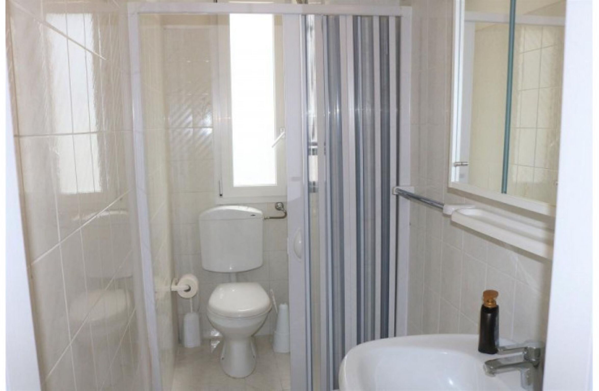 A bathroom with a toilet, a shower enclosure, and a sink.
