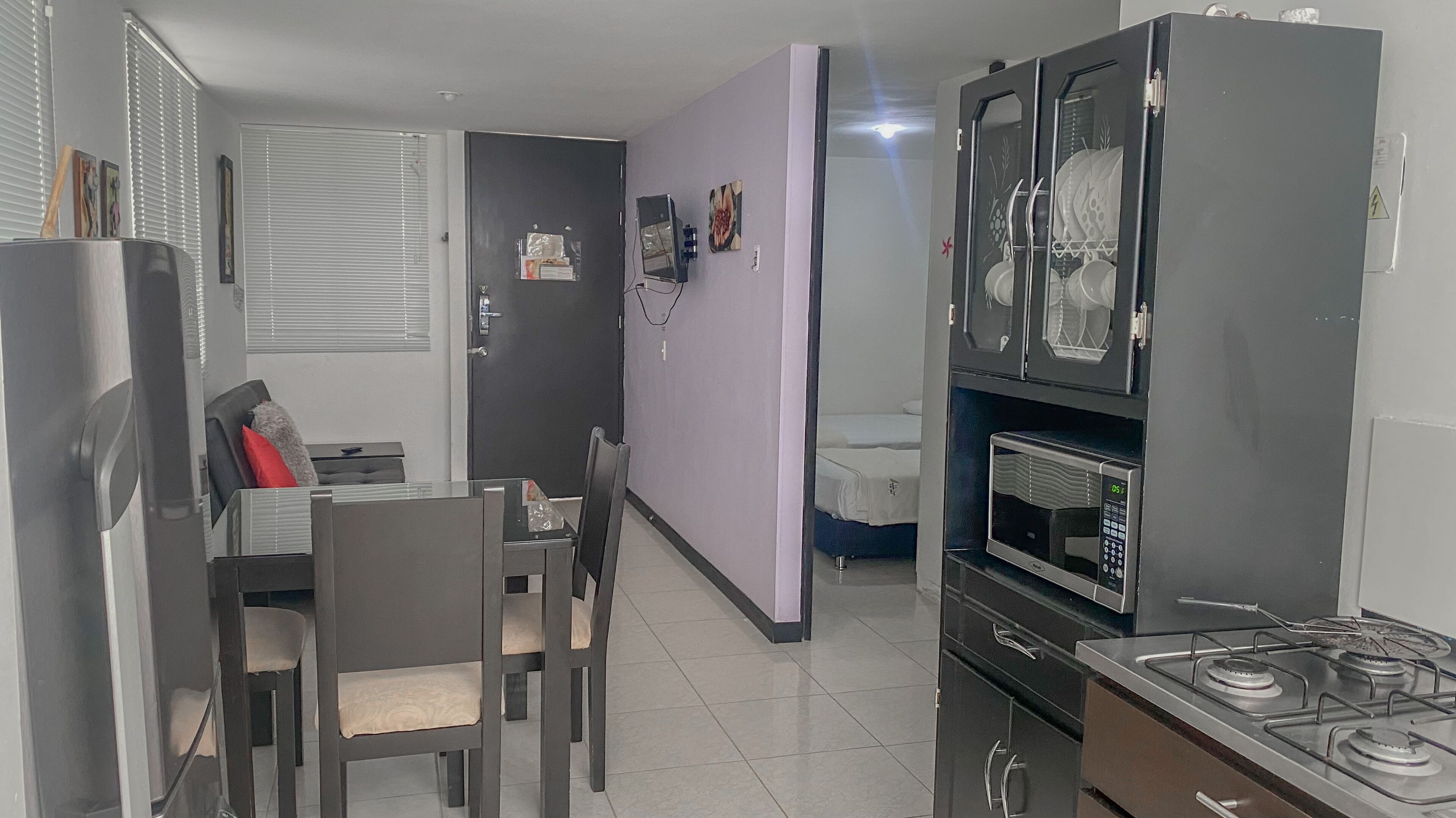 A compact kitchen with a gas stove, microwave, and a small dining area with chairs and a table.