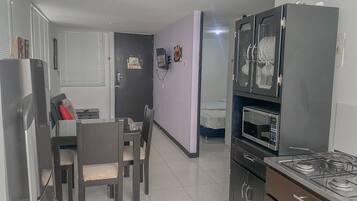 A compact kitchen with a gas stove, microwave, and a small dining area with chairs and a table.