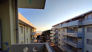 Un immeuble résidentiel à plusieurs étages, doté de balcons, offrant une vue sur la plage et s’ouvrant sur un ciel dégagé.
