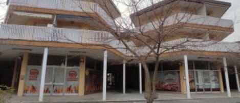 A multi-story building with a flat roof and a covered entrance area.