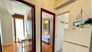 Habitación compacta con cama, una mesa de comedor y una zona de cocina con refrigerador.