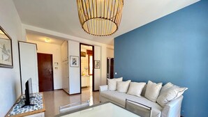 Una sala de estar moderna con un sofá blanco, una mesa de centro de vidrio y una lámpara colgante original.