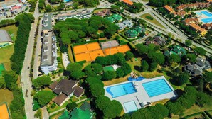 Vista aerea di una zona residenziale con case, una piscina e un campo da tennis.