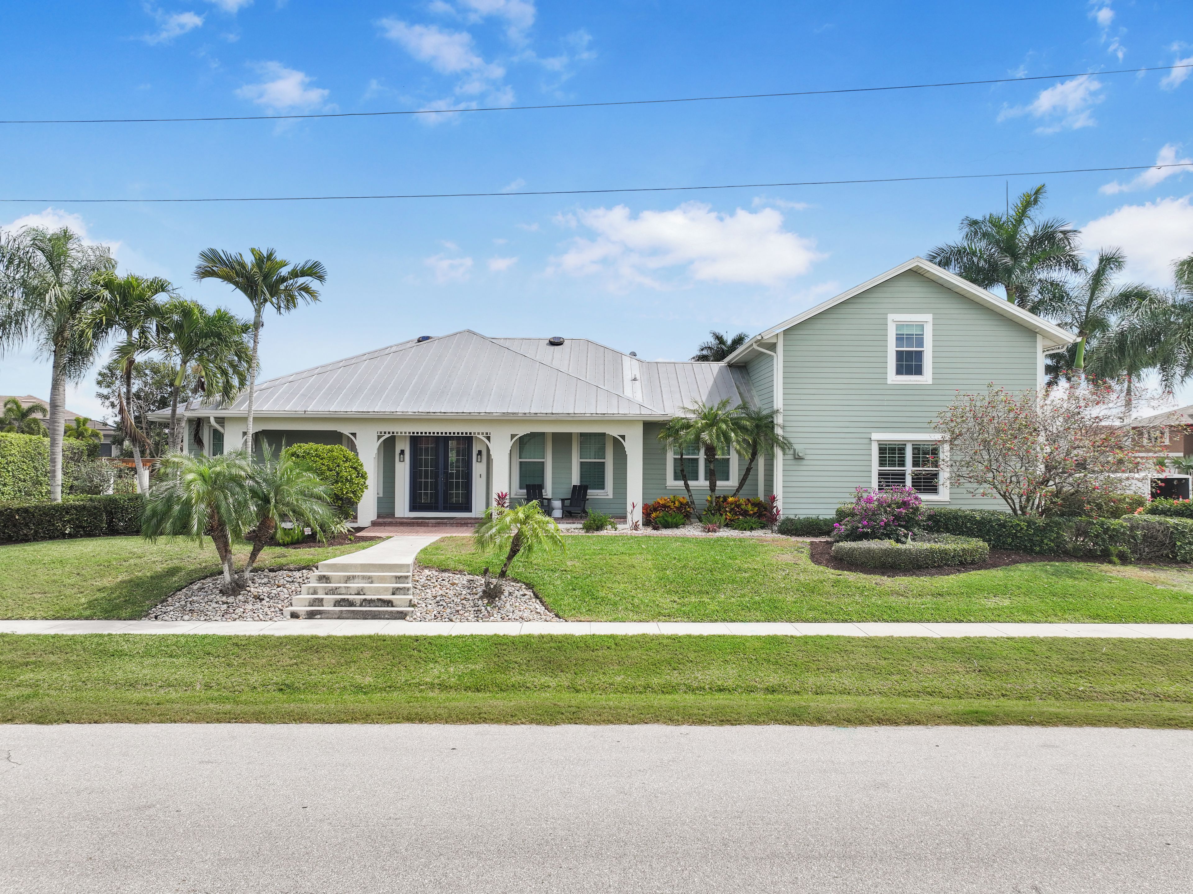 A two-story house with a covered porch, a front lawn, and a driveway.