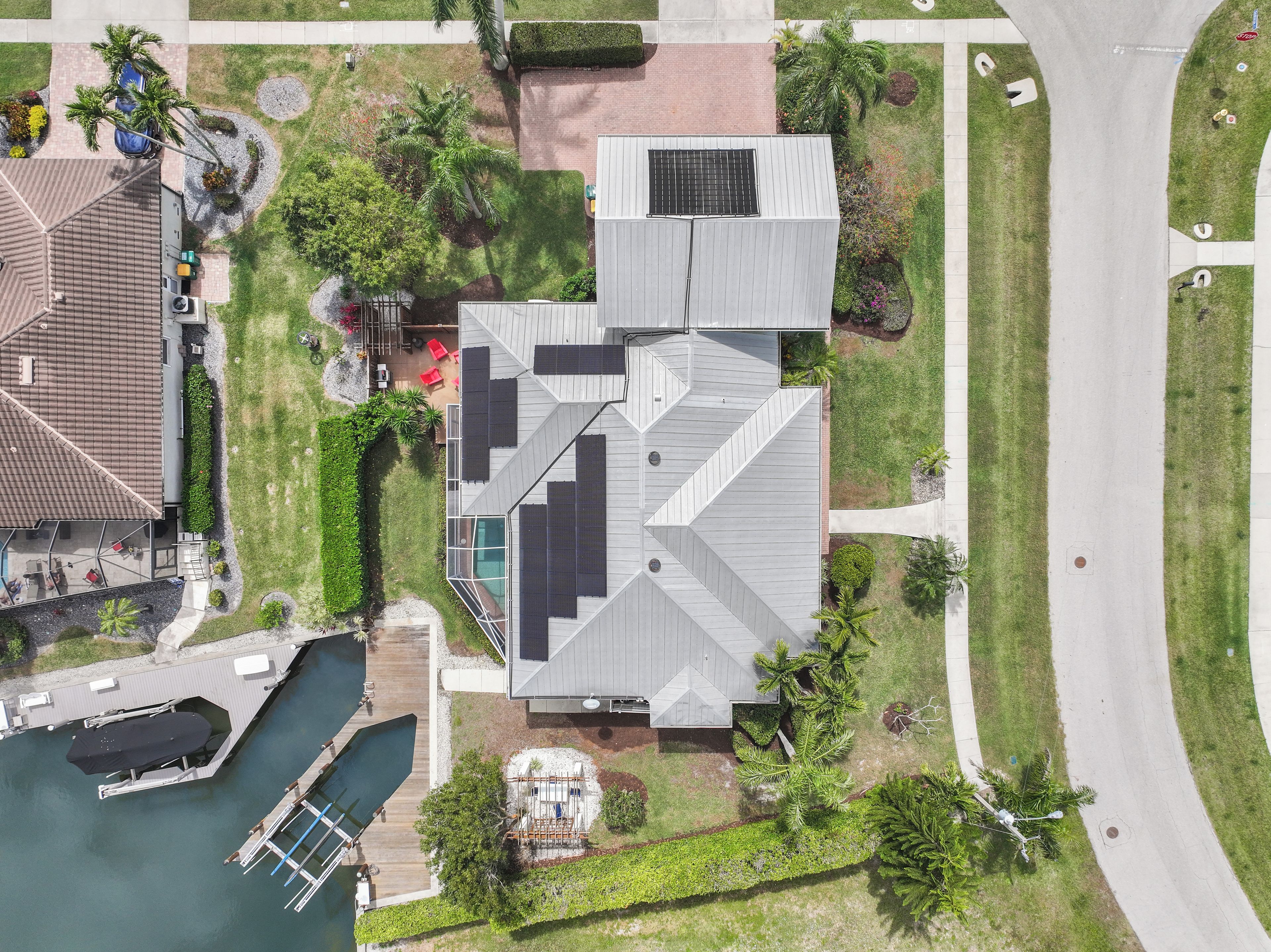 A residential property with a swimming pool, solar panels, and a dock.