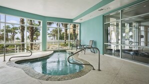 Un espace piscine avec vue sur les palmiers et un mur en verre.