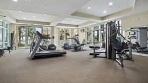 Une salle de sport spacieuse équipée de machines de cardio, de poids et d’un mur entièrement recouvert de miroirs.